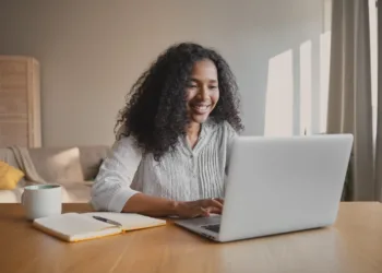 mulher jovem sorrindo olhando para notebook atendimento home office chat e-mail conversando digitando