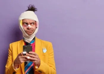 homem machucado curativos triste desconfiado com celular na mão roupa colorida consumidor frustrado