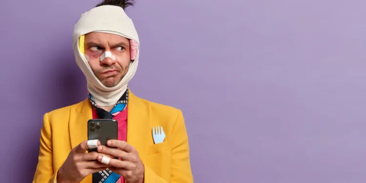 homem machucado curativos triste desconfiado com celular na mão roupa colorida consumidor frustrado